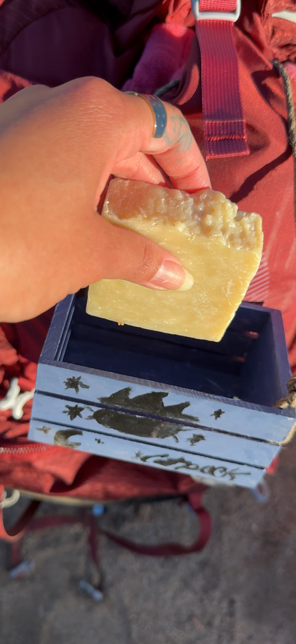 Hand holding a bar of soap over a blue box with a red background
